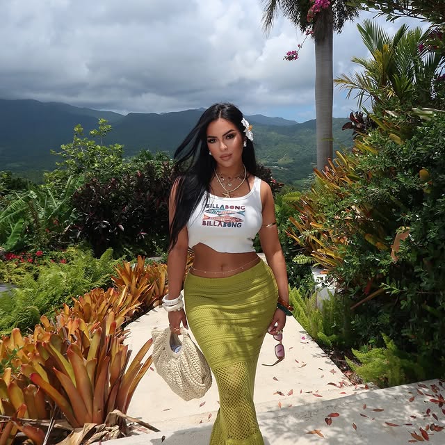 Cindy in a white top and green skirt in a tropical garden